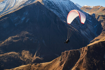 paragliding in the Caucasian mountains. In the background are mountain peaks covered in snow....