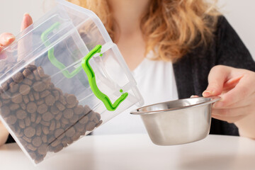 pet food storage, the owner pours dry food from the container box into the dog bowl, cat feed
