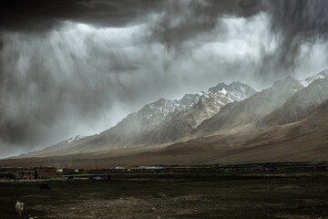 The towering snow-capped mountains are about to be covered by storm