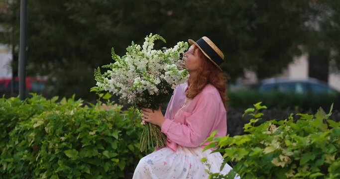 woman in pink shirt holding a bouquet of white flowers on the background of green garden, summer, spring concept. 4k footage