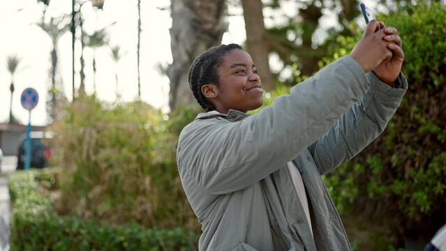 African american woman recording video by smartphone at park