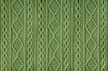 green background knitted fabric with a pattern. Knitted Arans close-up