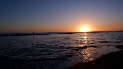 Sunset on the sea, waves crashing on the beach and the silhouette of Poseidon.