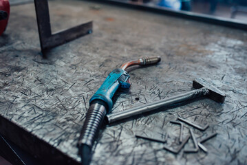 A hammer and a modern welding machine on a steel industrial table