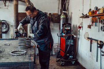 Locksmith in special clothes and goggles works in production. Metal processing with angle grinder. Sparks in metalworking.