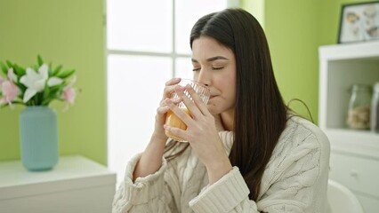 Young beautiful hispanic woman drinking orange juice suffering for teeth pain at home - Powered by Adobe