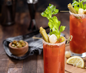 Bloody mary cocktail with garnishes on dark wooden background