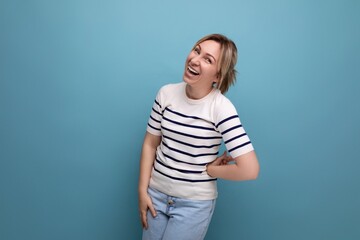 horizontal photo of bright cheerful happy blonde woman in casual outfit on blue background with copy space