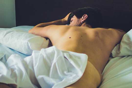 Sensuale ragazzo nudo dorme tra bianche lenzuola