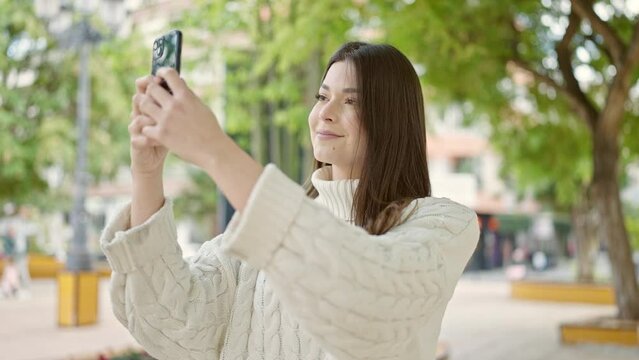 Young beautiful hispanic woman smiling confident making photo by the smartphone at park