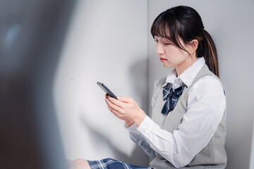 スマホを見ながら落ち込む女子高生