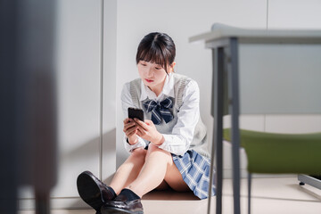 スマホを見ながら落ち込む女子高生