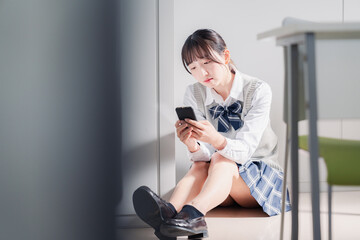 スマホを見ながら落ち込む女子高生