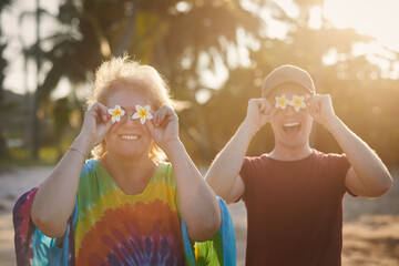 Funny portrait of happy senior woman with her adult son during travel in tropical destination..