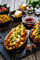 Roasted aubergine stuffed with minced meat and cheese  on wooden table
