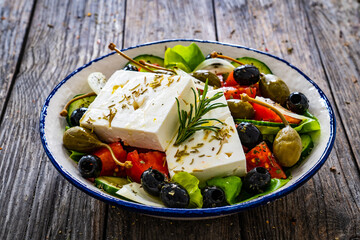 Fresh vegetable salad with feta cheese on wooden table
