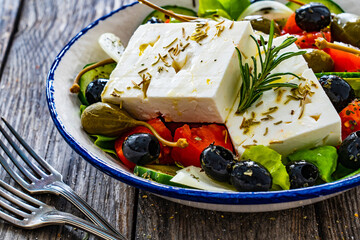 Fresh vegetable salad with feta cheese on wooden table
