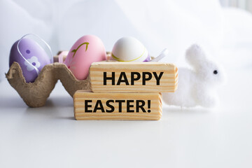 Colorful decorative eggs and HAPPY EASTER text close-up, against the background of a white rabbit
