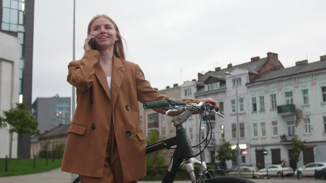 Young woman with bicycle talking on mobile phone outdoors