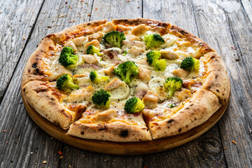 Circle pizza broccoli with chicken nuggets and mozzarella cheese on wooden table
