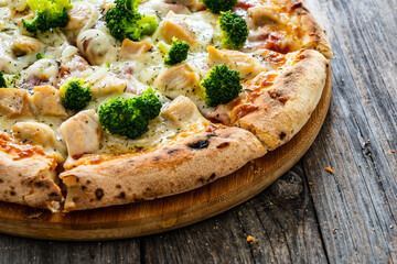 Circle pizza broccoli with chicken nuggets and mozzarella cheese on wooden table
