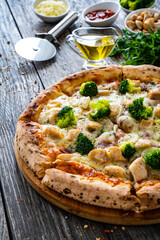 Circle pizza broccoli with chicken nuggets and mozzarella cheese on wooden table
