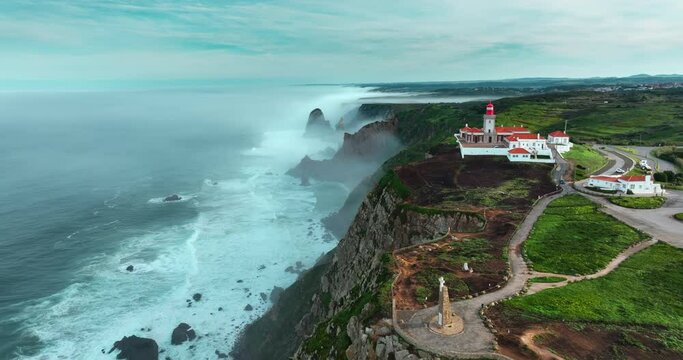 Aerial view pf the most western point of the European continent - Cabo da Roca, Portugal. Drone flies over the Atlantic ocean coast, rocky formations and the beach called Praia da Ursa.