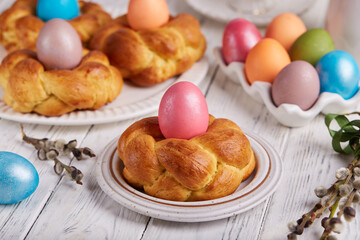 Traditional Easter bun bread in a shape of wreath made from yeast dough decorated with colored egg. Traditional Easter symbols and food. Easter baking