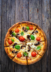 Circle vegetarian pizza with mozzarella cheese, mushrooms and tomatoes on wooden table
