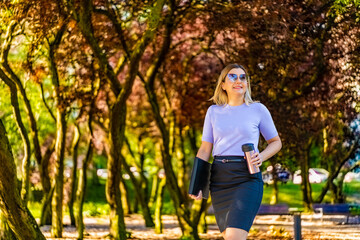 Coffee break - beautiful woman walking in city park
