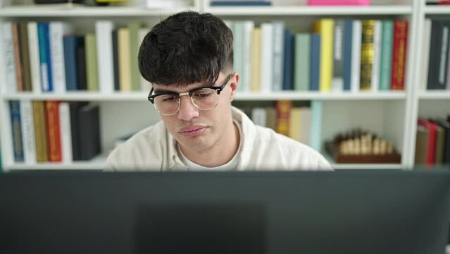 Young hispanic man student tired using computer yawning at library university
