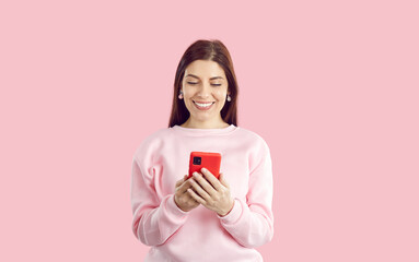 Portrait of attractive cheerful amazed girl using device smartphone gadget app isolated over bright pink color background. Smm specialist at work. Online shopping with mobile phone.