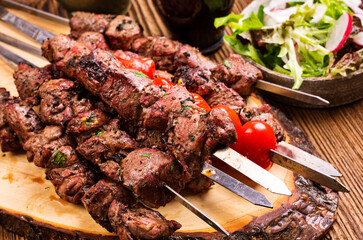 Traditional Russian shashlik on a barbecue skewer with vegetable and chili as top view on an old...