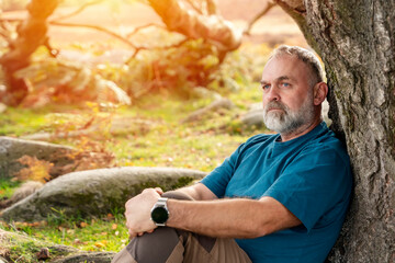 tired bearded man in special boots   reaching the destination and resting under tree in Peak District at sunset on autumn day Travel  Lifestyle concept