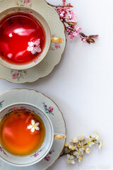 Zwei Teetassen mit rotem und gelbem Tee von oben mit viel Textfreiraum auf weißem Hintergrund, close-up vertikal