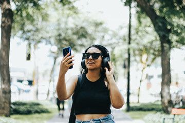 Photo of a woman listening to music with wireless headphones while wearing sunglasses. Lifestyle concept.