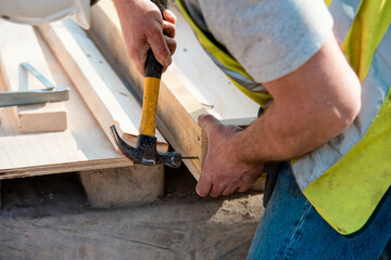 Carpenter hammering nail into the wood by hammer. Joiner with hammer and nail close-up
