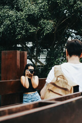 Photograph of woman taking pictures with a camera to a man. Vacation, tourism, and lifestyle concept.