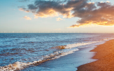 Sand beach, sea and cloudy blue sky in England at sunset