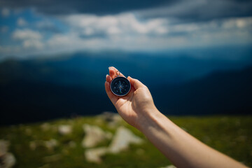 Traveler with compass seeking a right way in the mountains during hike. Navigation concept in explore travel.