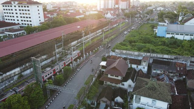 Aerial view of passenger train crossing rail bridge in near Tugu Station.