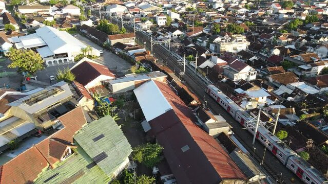 Aerial view of passenger train crossing rail bridge in near Tugu Station.