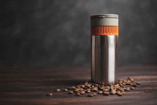 Thermos for coffee on a dark background with scattered coffee beans