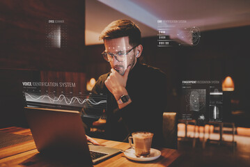Biometric security, the hologram of online security. Biometric security of eye, voice, finger and face. A man using a laptop in a cafe. 