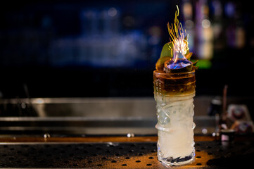 bartender makes flame over a cocktail with a burning fire in bar