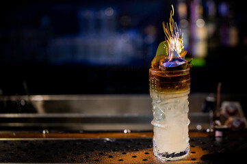 bartender makes flame over a cocktail with a burning fire in bar