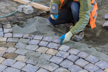 Worker were carefully laying granite stones and using industrial cobblestones to create durable and...