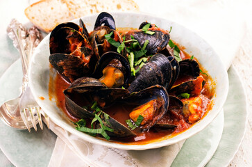 Traditional Italian mussels und red wine tomato sauce  with blue mussels served as close-up in a design plate