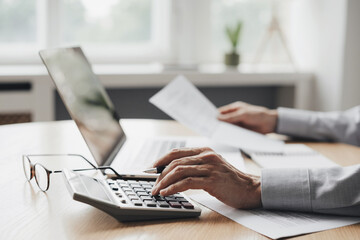 Man accountant using calculator and laptop computer in office, finance and accounting concept