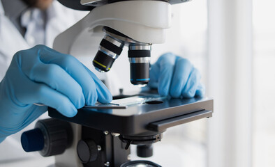 Medical laboratory, scientist hands using microscope for examining samples and liquid, Scientific and healthcare research background